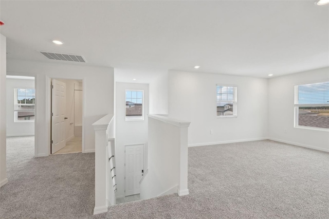 interior space with a wealth of natural light, visible vents, light carpet, and recessed lighting