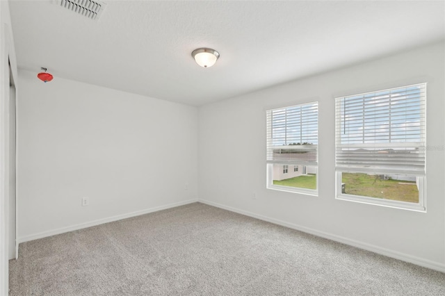 empty room with baseboards, visible vents, and carpet flooring