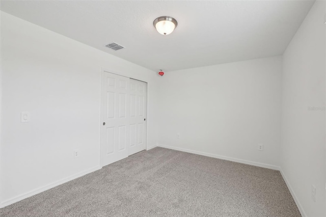 carpeted spare room featuring visible vents and baseboards