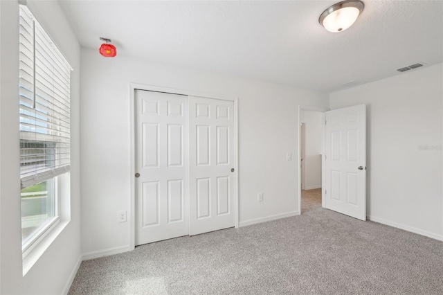 unfurnished bedroom with light colored carpet, visible vents, and baseboards