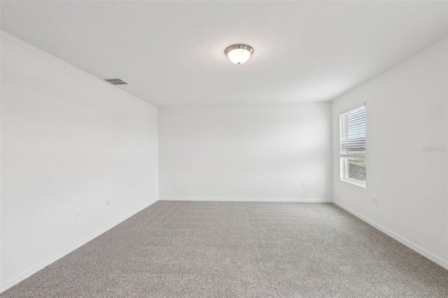 unfurnished room featuring carpet flooring, visible vents, and baseboards