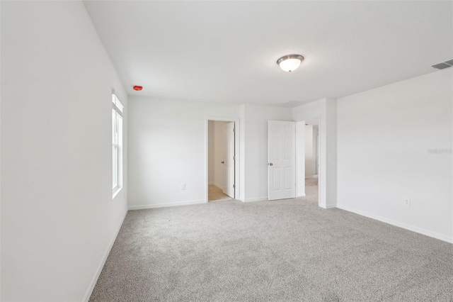 spare room with visible vents, baseboards, and carpet flooring