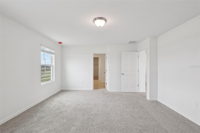 carpeted empty room with visible vents and baseboards