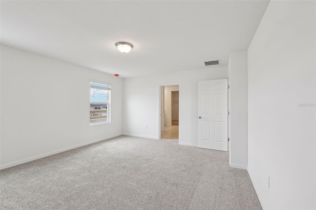 carpeted spare room featuring visible vents and baseboards