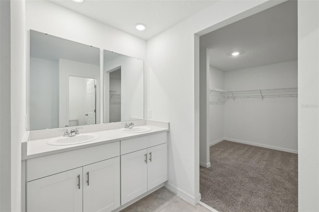 bathroom featuring double vanity, a spacious closet, toilet, and a sink