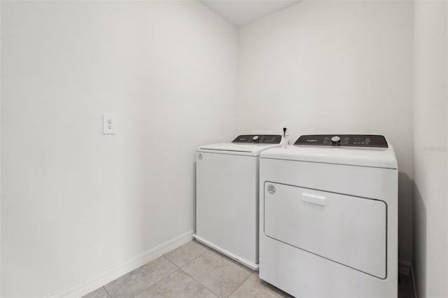 clothes washing area with laundry area, light tile patterned flooring, washer and clothes dryer, and baseboards