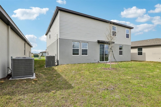 back of property with stucco siding, cooling unit, and a yard