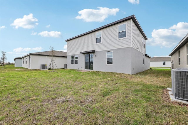 rear view of property with cooling unit, a yard, and stucco siding