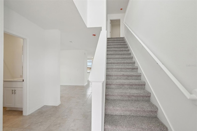 staircase with baseboards and tile patterned floors