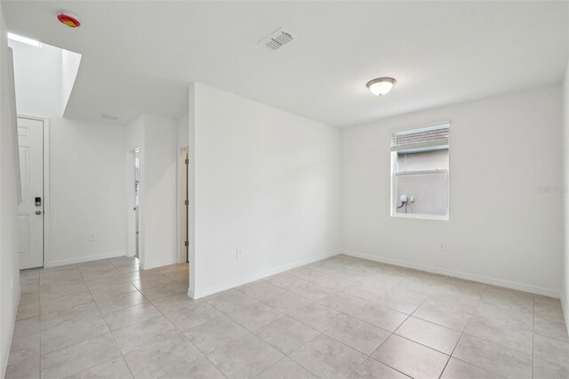 spare room with light tile patterned floors, visible vents, and baseboards