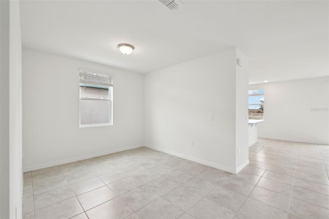 unfurnished room featuring light tile patterned flooring, visible vents, and baseboards