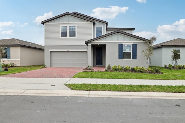 view of front facade featuring a garage, decorative driveway, board and batten siding, and a front yard