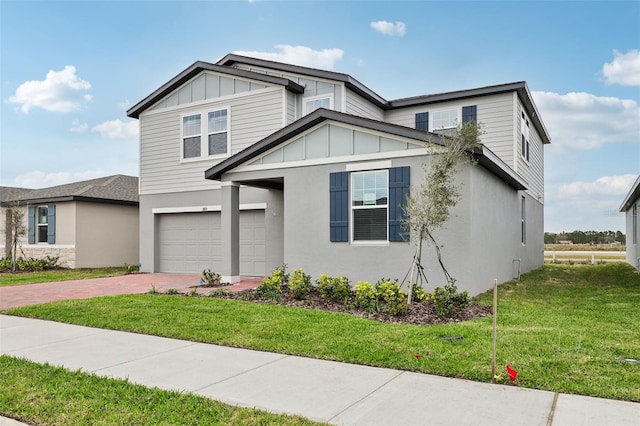 view of front of house with an attached garage, decorative driveway, a front lawn, and board and batten siding