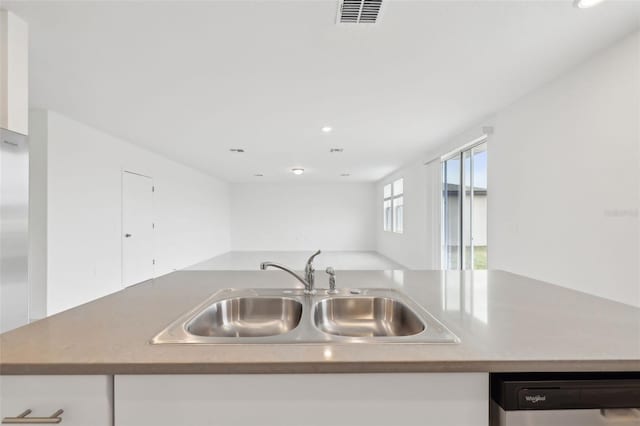 kitchen with visible vents, white cabinets, dishwasher, open floor plan, and a sink