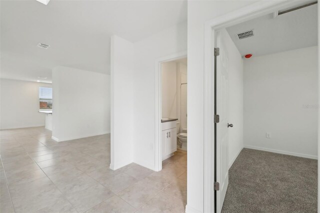 hall featuring light tile patterned floors, baseboards, and visible vents