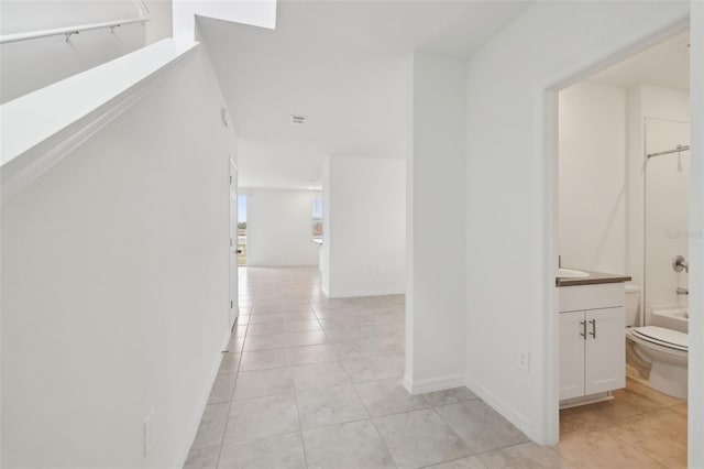 hallway featuring light tile patterned flooring and baseboards