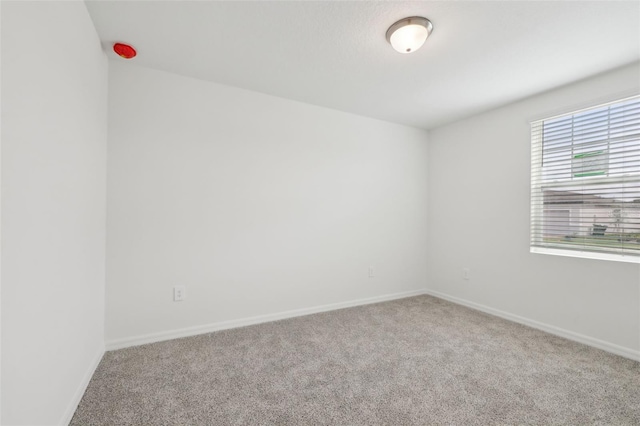 unfurnished room featuring carpet and baseboards