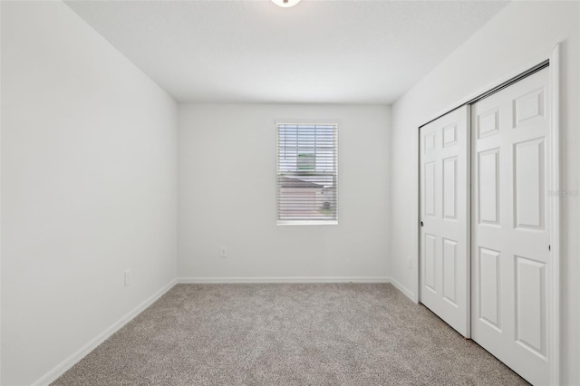 unfurnished bedroom with carpet, a closet, and baseboards