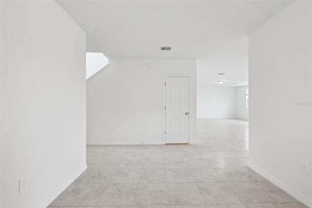 additional living space with light tile patterned floors, visible vents, and baseboards