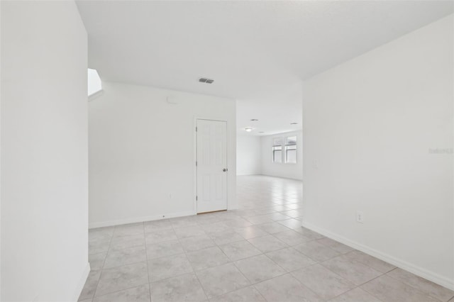 empty room featuring light tile patterned floors, baseboards, and visible vents