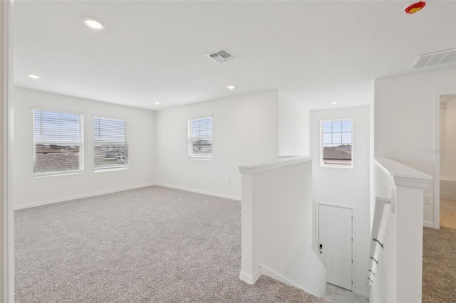 spare room with recessed lighting, light colored carpet, visible vents, and baseboards