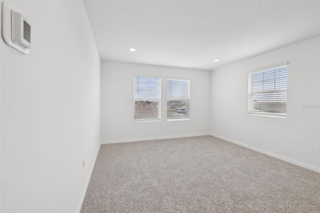 carpeted spare room featuring plenty of natural light, baseboards, and recessed lighting