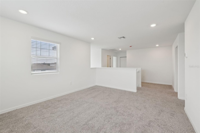 empty room featuring light carpet, baseboards, visible vents, and recessed lighting