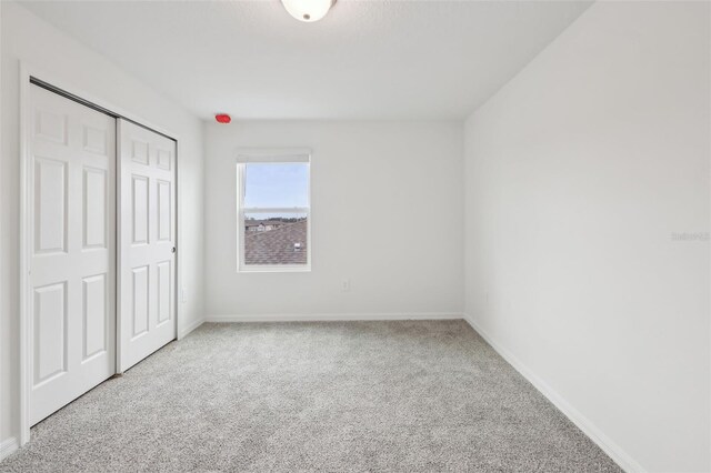 unfurnished bedroom with carpet floors, a closet, and baseboards