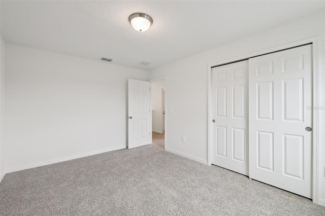 unfurnished bedroom with carpet, a closet, visible vents, and baseboards