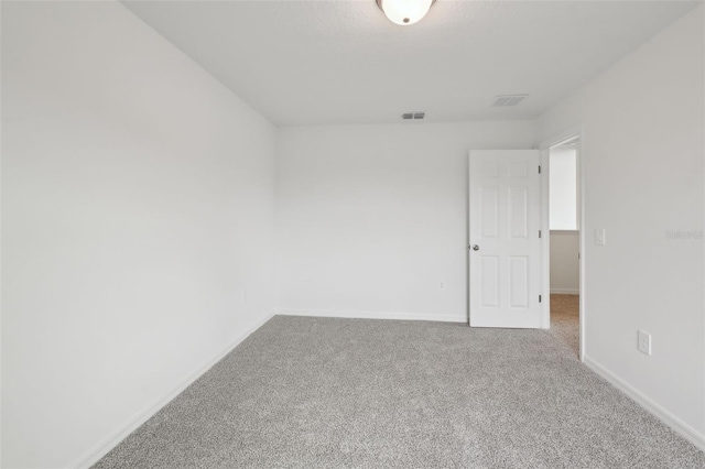 carpeted spare room featuring visible vents and baseboards