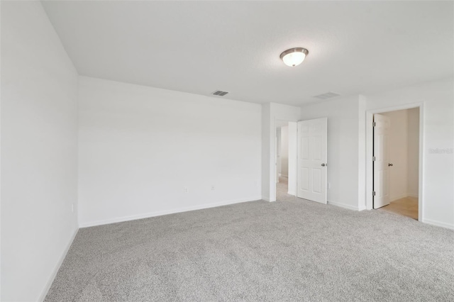 empty room with baseboards, visible vents, and carpet flooring