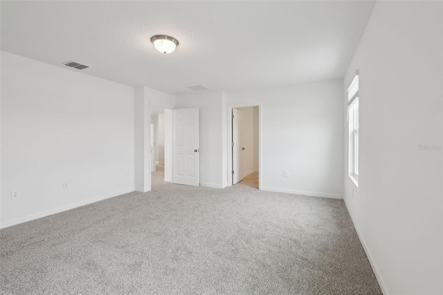 empty room with light colored carpet, visible vents, and baseboards