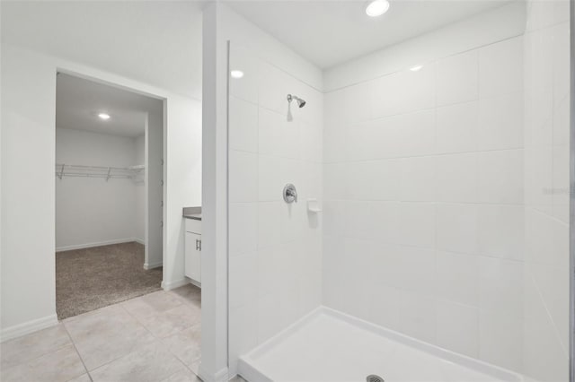 bathroom with a spacious closet, recessed lighting, a tile shower, and tile patterned floors