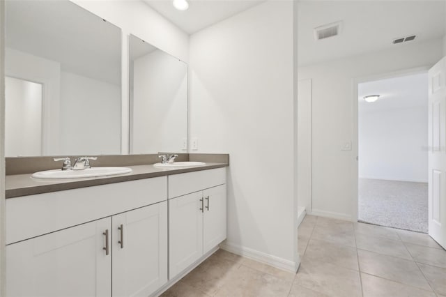 full bathroom featuring double vanity, baseboards, a sink, and tile patterned floors