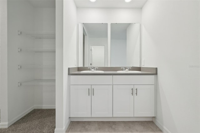 full bath with double vanity, a sink, and baseboards