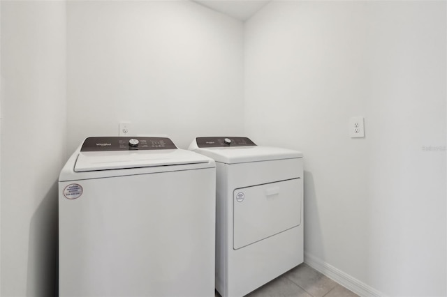 washroom featuring laundry area, baseboards, washer and clothes dryer, and light tile patterned flooring