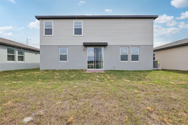 rear view of house with cooling unit, a lawn, and stucco siding