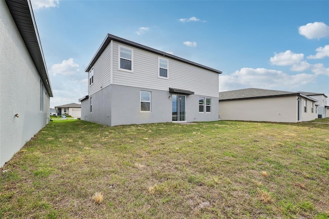 rear view of property with a lawn and stucco siding