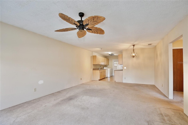 unfurnished living room with a textured ceiling, ceiling fan with notable chandelier, light colored carpet, and washing machine and dryer