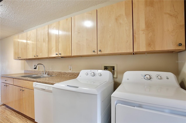 laundry area featuring washer and dryer, sink, a textured ceiling, and light wood-type flooring