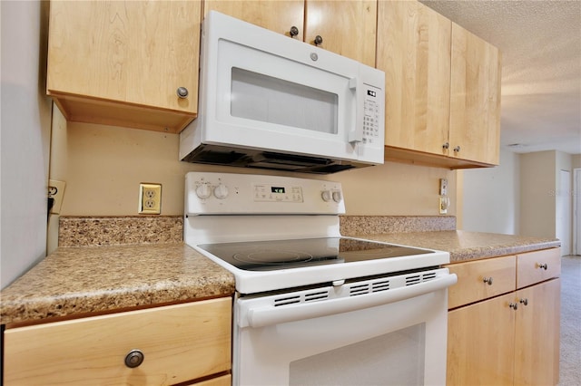 kitchen with white appliances, light brown cabinets, and a textured ceiling