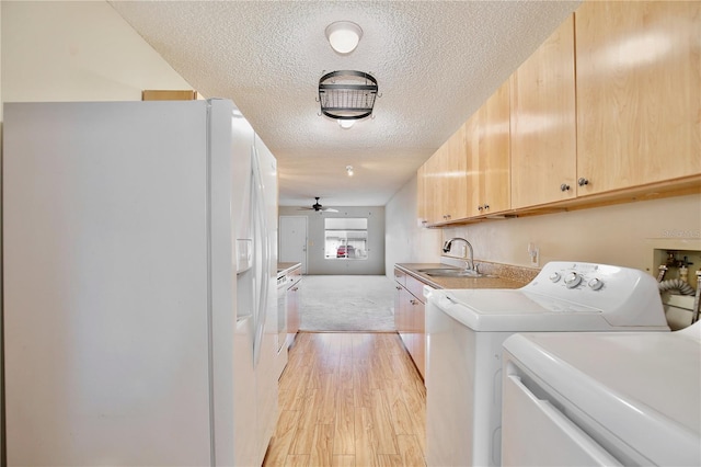 laundry area with ceiling fan, sink, light wood-type flooring, washer and dryer, and a textured ceiling