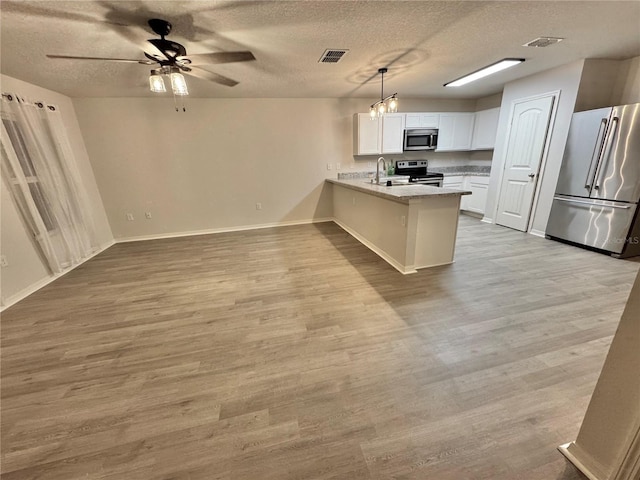 kitchen with a peninsula, wood finished floors, visible vents, white cabinets, and appliances with stainless steel finishes