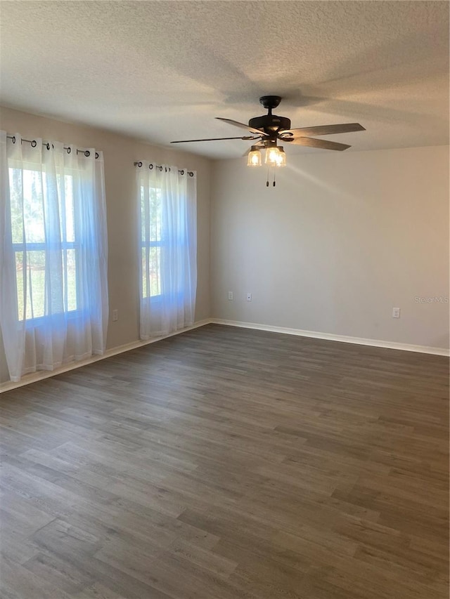 spare room featuring dark wood-style floors, baseboards, and a textured ceiling