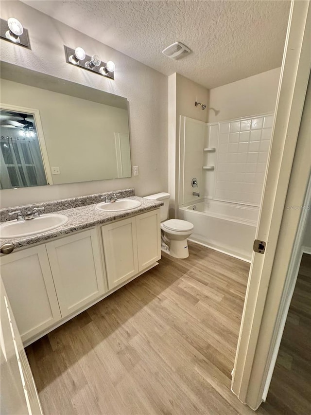 full bathroom with washtub / shower combination, visible vents, a sink, and wood finished floors