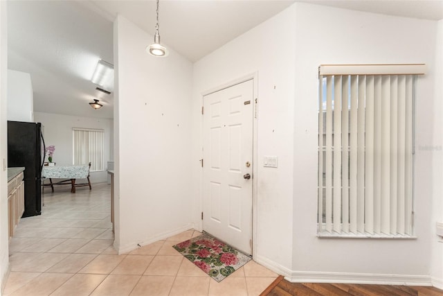 tiled entryway featuring vaulted ceiling