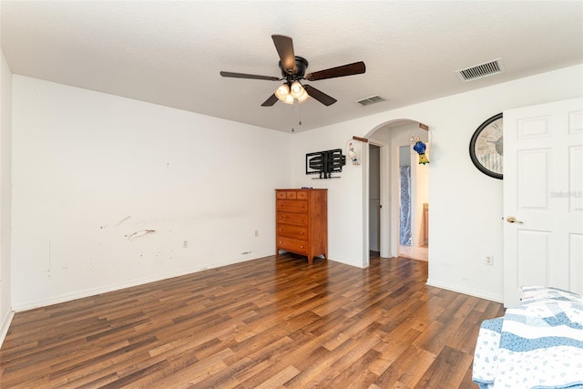 unfurnished bedroom with dark wood-type flooring, a textured ceiling, and ceiling fan