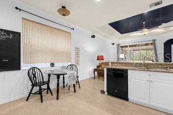 kitchen featuring white cabinetry, black dishwasher, and a sink