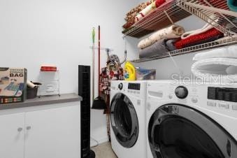 clothes washing area featuring cabinet space and separate washer and dryer