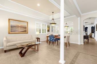 living room with crown molding, baseboards, and decorative columns